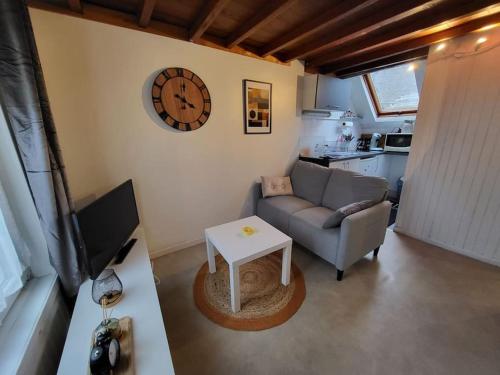 een woonkamer met een bank en een klok aan de muur bij Charmant appartement au cœur du quartier St-Pierre in Amiens