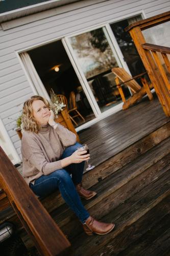 a woman sitting on a porch holding a glass of wine at Page's Inn on Silva Bay in Gabriola