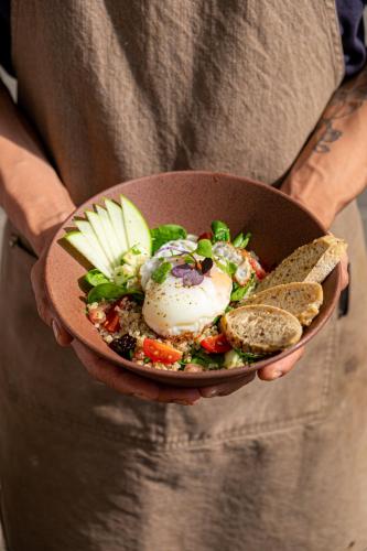 a person holding a bowl of salad with an egg and bread at Nassau Suite South Beach, an All Suite Hotel in Miami Beach