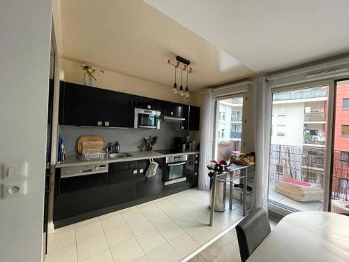 uma grande cozinha com armários pretos e uma mesa em Appartement 3 pièces RER C proche Paris Les Grésillons em Asnières-sur-Seine