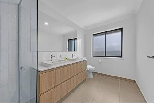 een badkamer met een wastafel, een douche en een toilet bij Brand New Home In Oran Park in Narellan