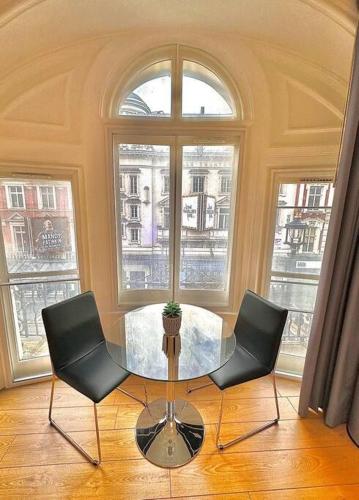 een tafel en 2 stoelen in een kamer met ramen bij V05 Fantastic Apartment - Piccadilly Circus on Doorstep! in Londen