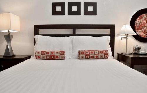a bedroom with a large white bed with two pillows at El Primero Boutique Hotel in Chula Vista