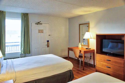 um quarto de hotel com uma cama, uma secretária e uma televisão em Motel 6-Buffalo, NY - Airport - Williamsville em Williamsville