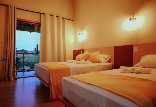 a hotel room with two beds and a window at Pousada Paudoro in Conceição do Mato Dentro