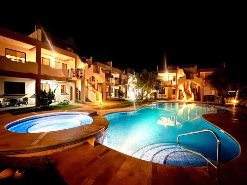 a large swimming pool in front of some buildings at night at Sunny Tropical Condo And Rooftop Terrace in Coco