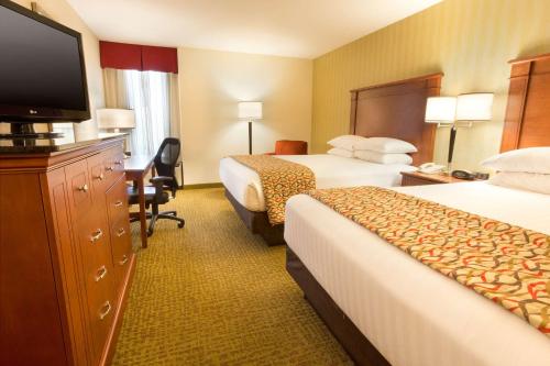 a hotel room with two beds and a flat screen tv at Drury Inn & Suites Charlotte University Place in Charlotte