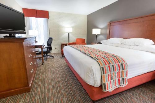 a hotel room with a bed and a flat screen tv at Drury Inn & Suites Joplin in Joplin