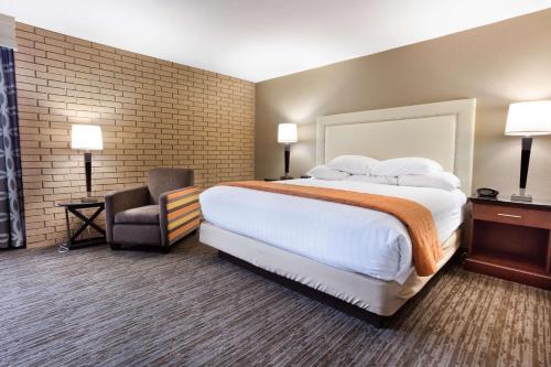 a hotel room with a large bed and a chair at Drury Inn & Suites Kansas City Airport in Kansas City