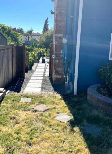 a yard with a blue building and a fence at Studio in West Seattle in Seattle