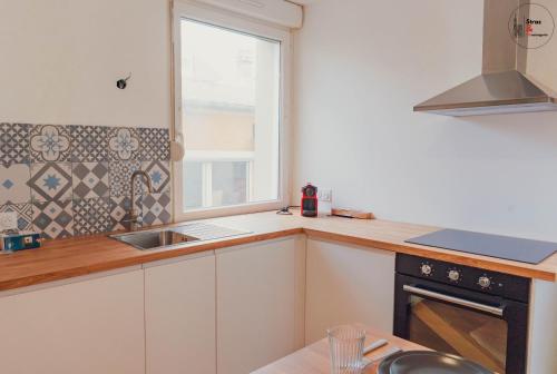 uma cozinha com um lavatório e uma janela em Le reflet chic - 2 pièces neuf - quartier calme à 5 min de Strasbourg em Schiltigheim