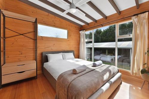 ein Schlafzimmer mit einem Bett und einem großen Fenster in der Unterkunft Mt Elephant Forrest Cabin 