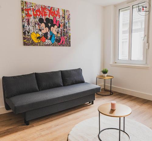 a living room with a couch and a painting on the wall at Le reflet chic - 2 pièces neuf - quartier calme à 5 min de Strasbourg in Schiltigheim