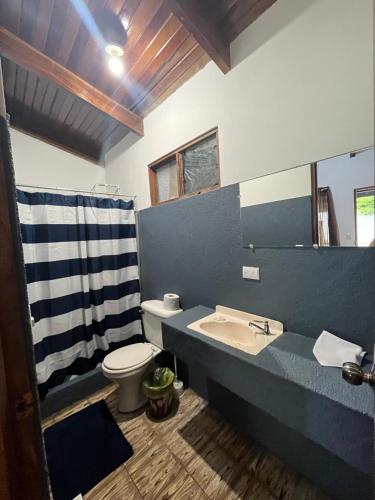 een badkamer met een wastafel, een toilet en een spiegel bij #2 Cabina Rústica para 3 personas en Paquera in Puntarenas