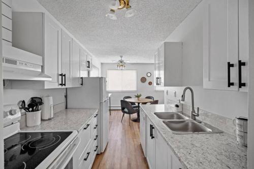 a kitchen with white cabinets and a sink and a table at Modern 2BR with Free Parking and Newly Renovated in Fort McMurray