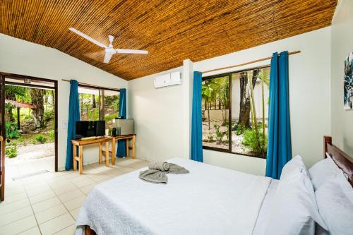1 dormitorio con 1 cama con cortinas azules y TV en El Sueno Tropical Hotel, en Carrillo