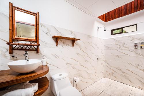 Baño blanco con lavabo y espejo en El Sueno Tropical Hotel, en Carrillo