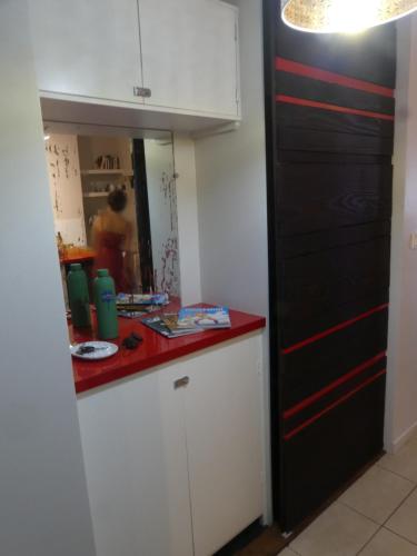 a kitchen with white cabinets and a red counter top at Studio Poe Rava in Papeete