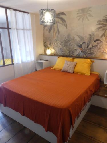 a bedroom with a bed with orange sheets and yellow pillows at Studio Poe Rava in Papeete