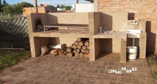 una barbacoa con una pila de leña. en A la sombra del calden en Santa Rosa