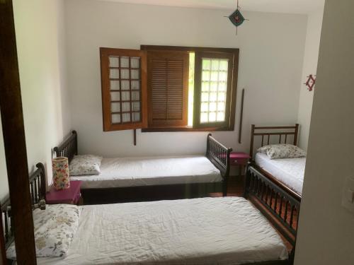 Cette chambre comprend 3 lits et une fenêtre. dans l'établissement Casa de Fazenda na Ecovila Sustentar, 38km de SP, à Embu-Guaçu