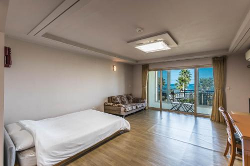 a bedroom with a bed and a couch and a window at Sea Eco Beach in Jeju