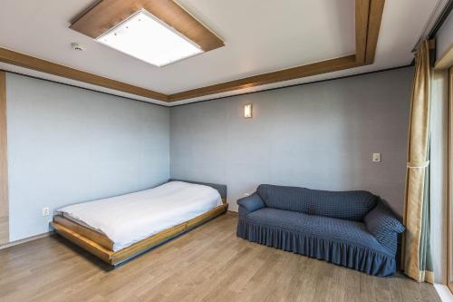 a bedroom with a bed and a couch and a skylight at Sea Eco Beach in Jeju