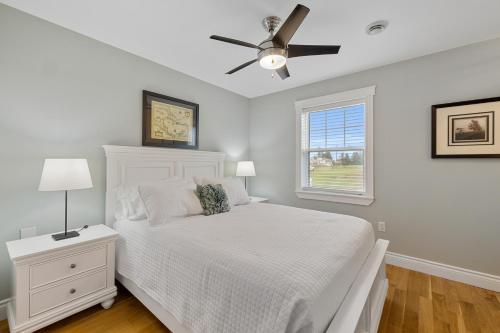 a bedroom with a white bed and a ceiling fan at Heron House in Stanley Bridge