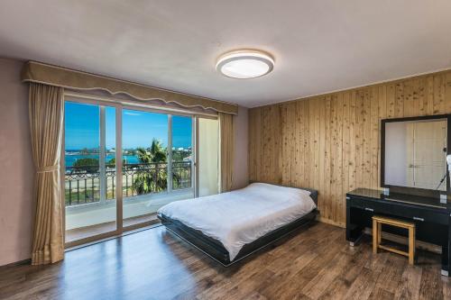 a bedroom with a bed and a desk and a window at Sea Eco Beach in Jeju