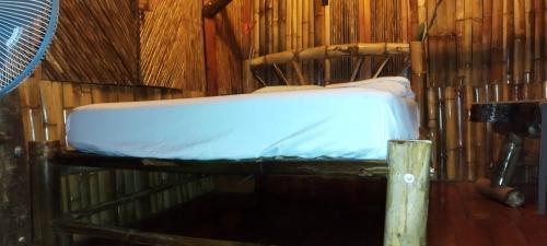 Cama en habitación de bambú con colchón en Hostal Inculta, en Santo Domingo