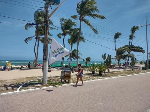 uma mulher a andar numa rua ao lado de uma praia em Morada do Francês na Praia do Francês