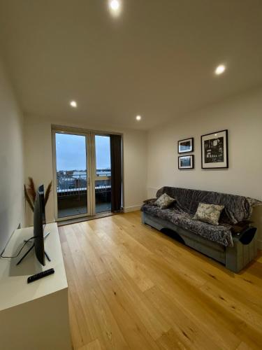 a living room with a couch and a television at Spacious 2 Bedroom Penthouse Retreat in London