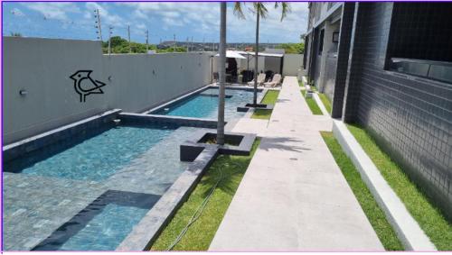 uma piscina ao lado de um edifício em Cobertura Vista Mar Carapibus - Cariri Praia - Apartamento completo com 02 quartos em Conde