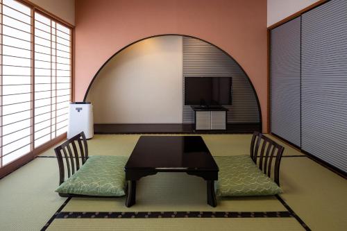a dining room with a table and chairs and a tv at Ooedo Onsen Monogatari Amakusa Hotel Kameya in Kami Amakusa