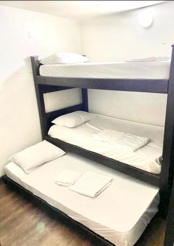 2 literas en una habitación con sábanas blancas en APARTAMENTOS En LAURELES ESTADIO, en Medellín