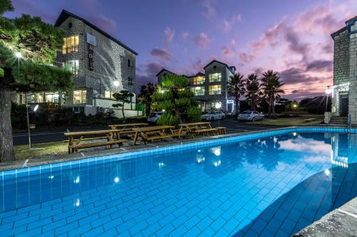 a swimming pool with benches and a building at Sea Eco Beach in Jeju