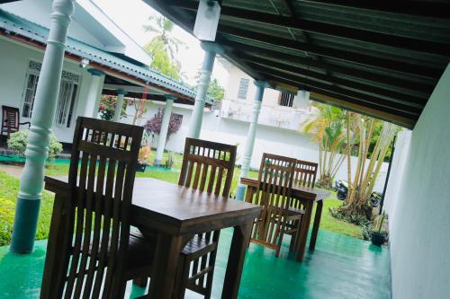 een houten tafel en stoelen op een veranda bij The White Villa in Hikkaduwa
