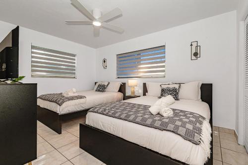 a bedroom with two beds and a ceiling fan at Charming home 12min to the Beach in Hallandale Beach