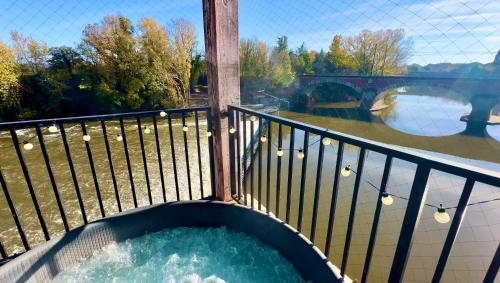 d'un bain à remous sur un balcon avec vue sur la rivière. dans l'établissement Suite prestige « Paradis » 5* au Moulin d’Albias, à Albias