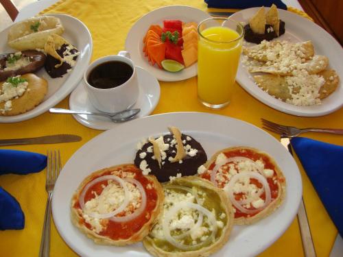 a table with plates of breakfast foods and drinks at Hotel Delfines in Veracruz