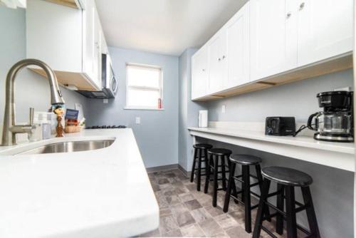 a kitchen with white cabinets and black bar stools at -- AGH Walkable - Free Parking - Washer & Dryer -- in Pittsburgh