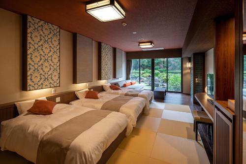 a row of beds in a room with windows at Ooedo Onsen Monogatari Amakusa Hotel Kameya in Kami Amakusa