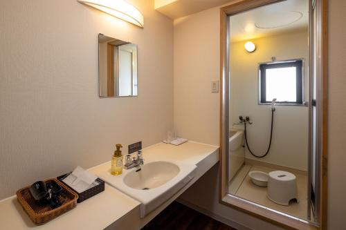 a bathroom with a sink and a shower with a mirror at Ooedo Onsen Monogatari Amakusa Hotel Kameya in Kami Amakusa