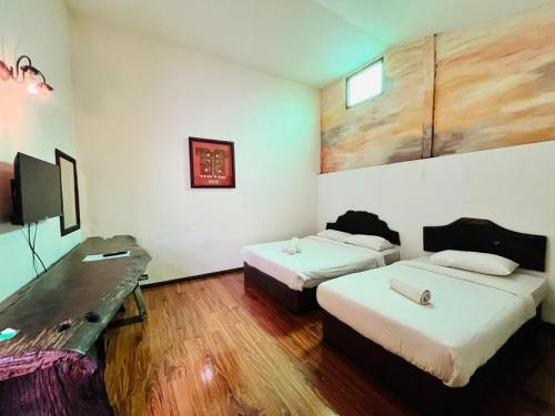 Habitación de hotel con 2 camas y escritorio en Kuching Waterfront Lodge, en Kuching