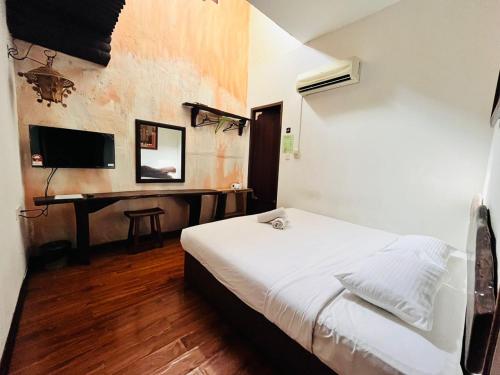 a bedroom with a bed and a desk with a television at Kuching Waterfront Lodge in Kuching
