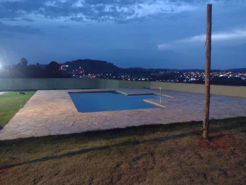 a swimming pool in the middle of a yard at night at Pedacinho do céu in Pinhalzinho