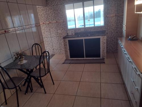 a kitchen with a table and a tv in a room at Pedacinho do céu in Pinhalzinho