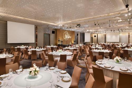 a conference room with tables and chairs and a projection screen at Le Meridien Taipei in Taipei