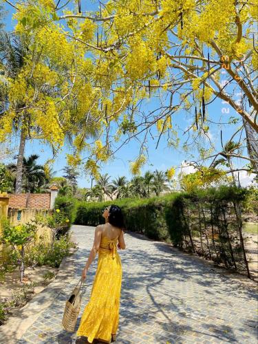 a woman in a yellow dress walking down a sidewalk at Full Moon Village Resort in Mui Ne