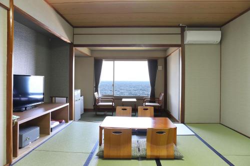 a living room with a table and a view of the ocean at Ooedo Onsen Monogatari Beppu Seifu in Beppu